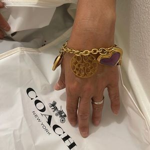 Ladies coach bracelet. Golden with some clear purple charms.